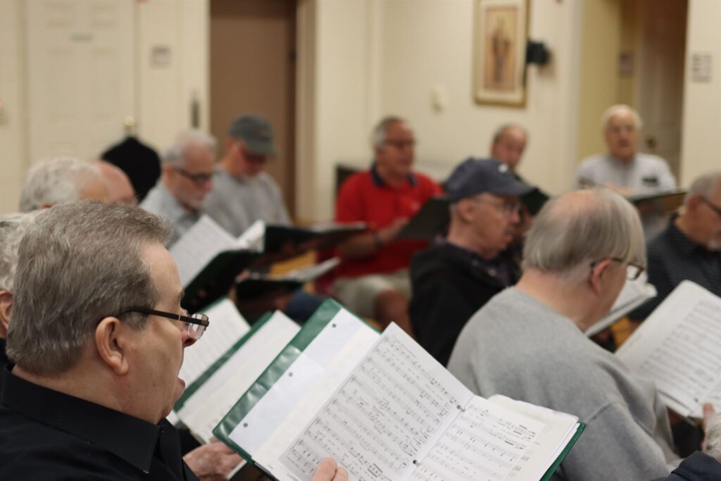 Men singing in a choir sitting down